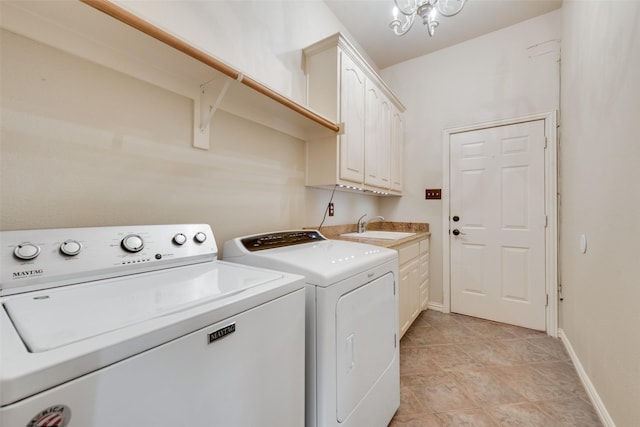 clothes washing area with a sink, baseboards, washing machine and dryer, and cabinet space
