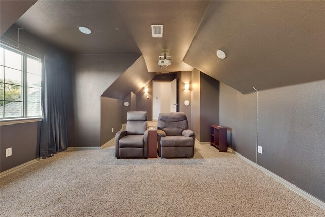 home theater featuring a textured ceiling, carpet, baseboards, lofted ceiling, and visible vents