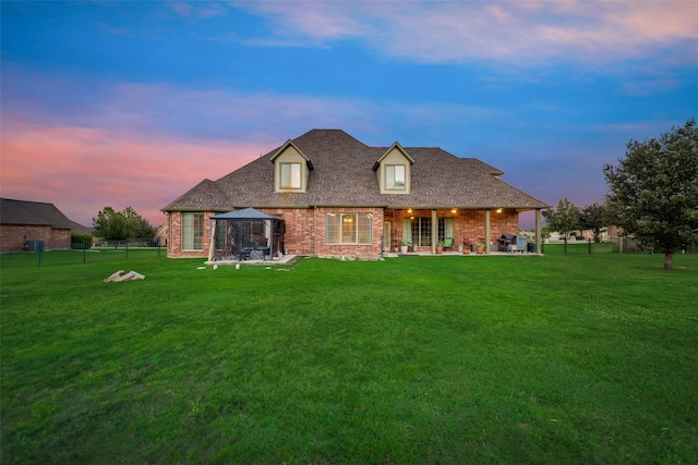 rear view of property with a lawn, a gazebo, a patio area, and brick siding