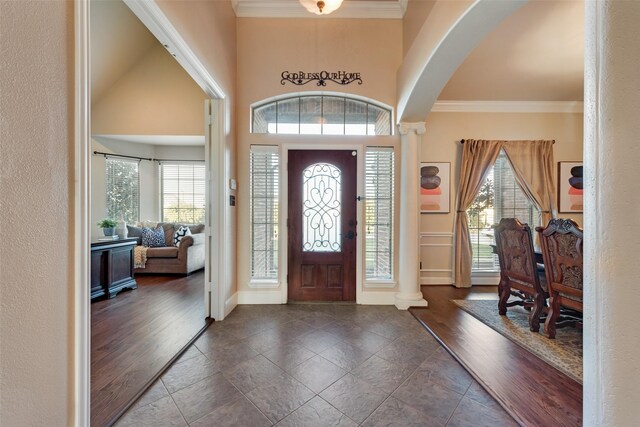 entryway featuring crown molding, arched walkways, baseboards, and wood finished floors