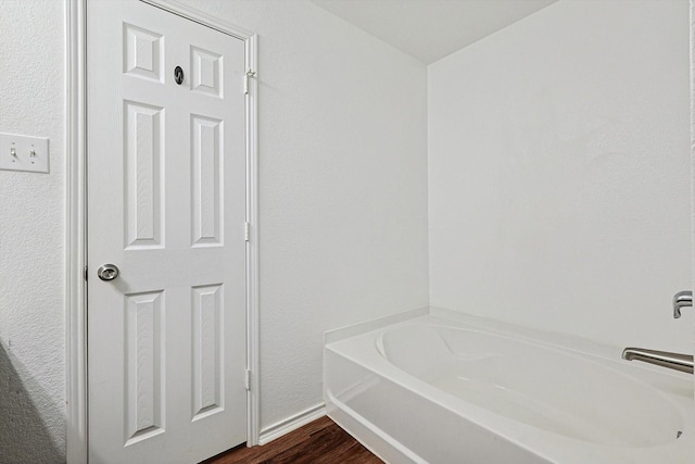 1225 Bellevue Dr, Princeton, TX 75407 - bathroom featuring baseboards, a tub to relax in, and wood finished floors