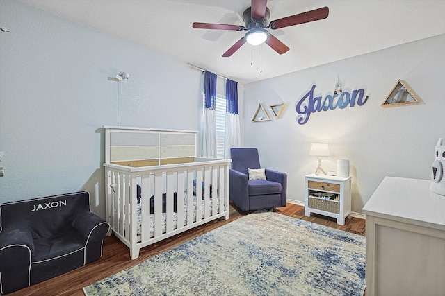 1225 Bellevue Dr, Princeton, TX 75407 - bedroom featuring a nursery area, ceiling fan, and wood finished floors