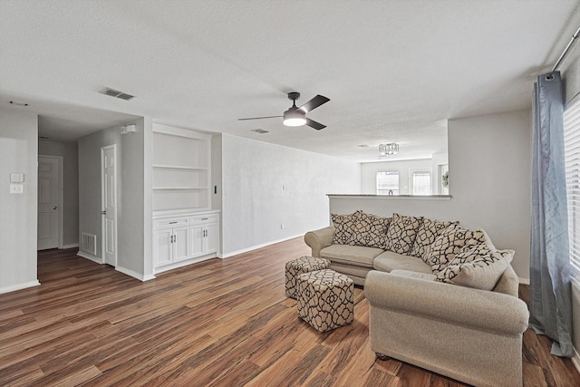 1225 Bellevue Dr, Princeton, TX 75407 - living area with visible vents, a ceiling fan, built in features, and dark wood-type flooring