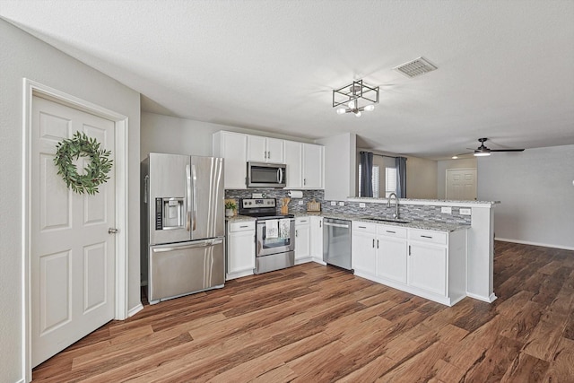 1225 Bellevue Dr, Princeton, TX 75407 - kitchen with visible vents, wood finished floors, a sink, a peninsula, and stainless steel appliances