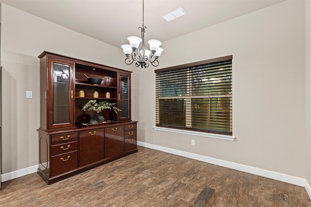 interior space with baseboards, visible vents, wood finished floors, and a notable chandelier