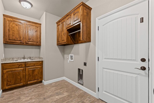 clothes washing area with hookup for an electric dryer, cabinet space, a sink, light wood finished floors, and hookup for a washing machine