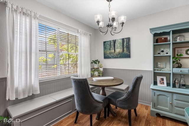 dining space featuring a chandelier, wainscoting, and wood finished floors
