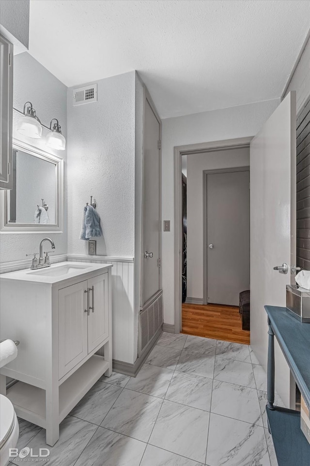 full bathroom with vanity, marble finish floor, a textured ceiling, and visible vents