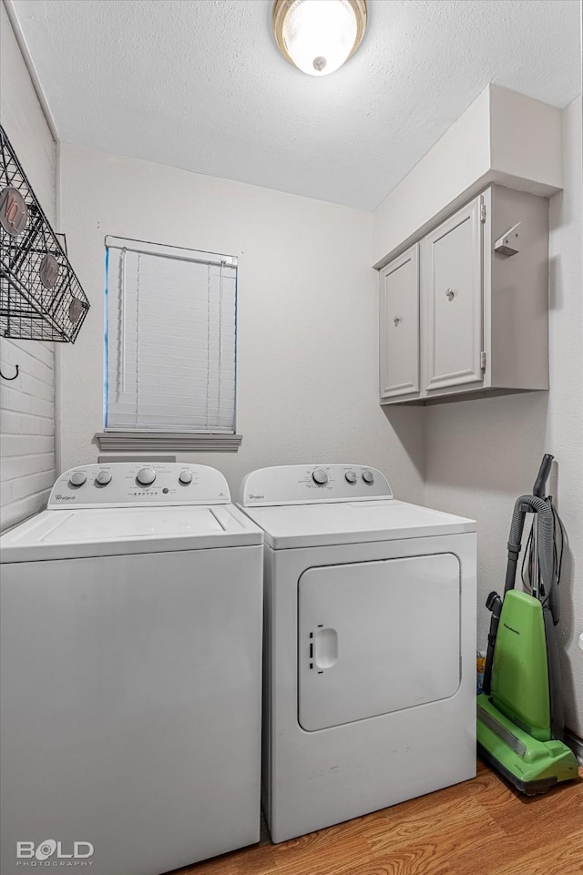 washroom with washer and dryer, a textured ceiling, light wood-style floors, and cabinet space