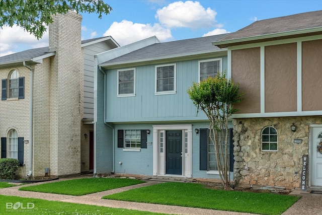 multi unit property with a front lawn and stone siding