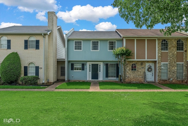 view of property featuring stone siding and a front yard