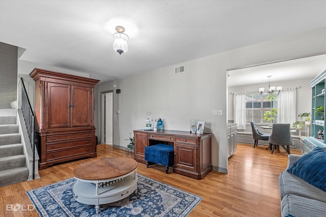 living area with stairs, an inviting chandelier, visible vents, and light wood-type flooring