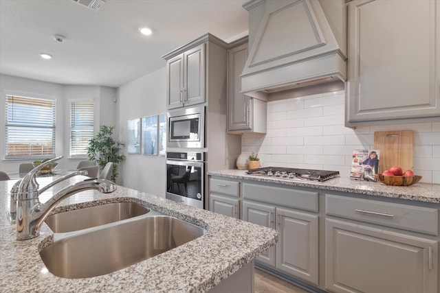 1008 Sublime Dr, Heath, TX 75126 - kitchen with gray cabinets, appliances with stainless steel finishes, tasteful backsplash, a sink, and custom range hood