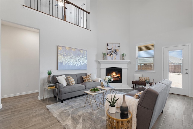 1008 Sublime Dr, Heath, TX 75126 - living area with baseboards, a warm lit fireplace, a high ceiling, and wood finished floors