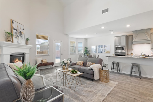 1008 Sublime Dr, Heath, TX 75126 - living area with a towering ceiling, visible vents, light wood finished floors, a glass covered fireplace, and recessed lighting