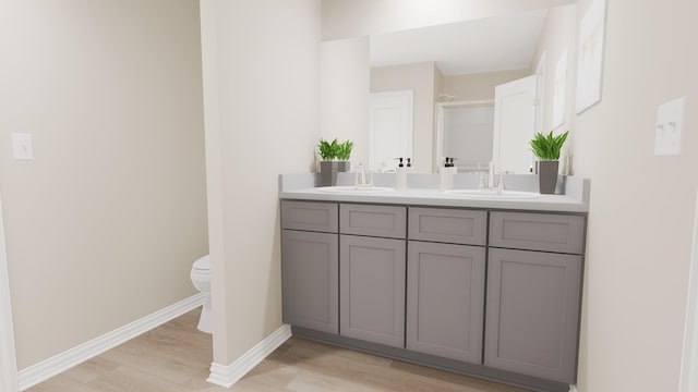 bathroom featuring double vanity, a sink, wood finished floors, and toilet