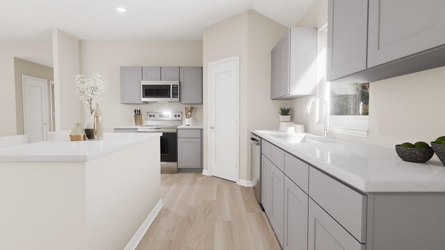 kitchen featuring stainless steel appliances, a sink, gray cabinets, and light wood-type flooring