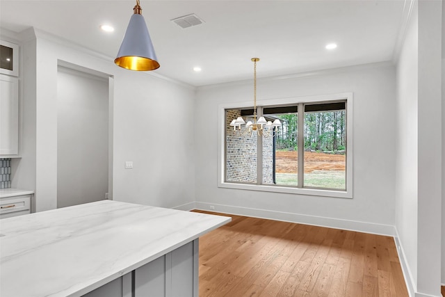 unfurnished dining area featuring baseboards, light wood finished floors, a chandelier, and visible vents