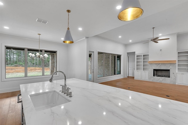 kitchen featuring visible vents, wood finished floors, a sink, light stone counters, and recessed lighting