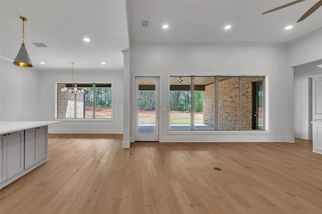 unfurnished living room featuring visible vents, crown molding, light wood-style flooring, and ceiling fan with notable chandelier