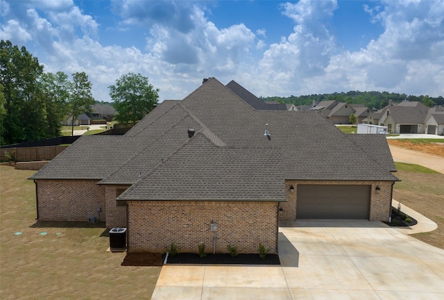exterior space featuring a garage, brick siding, a shingled roof, driveway, and a residential view