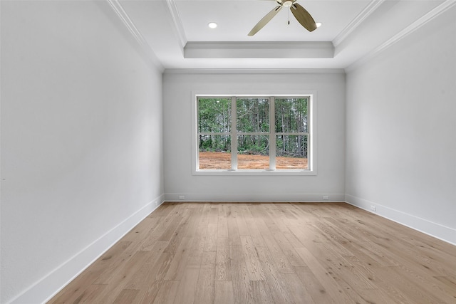 spare room featuring a raised ceiling, ornamental molding, a ceiling fan, and light wood-style flooring