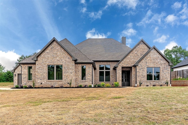 craftsman-style home with brick siding, a chimney, roof with shingles, and a front lawn