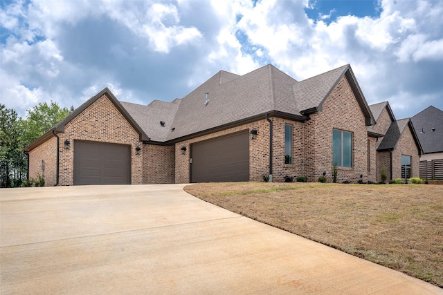 view of front of property featuring driveway, brick siding, a front lawn, an attached garage, and a shingled roof