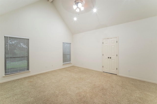 empty room featuring ceiling fan, light colored carpet, high vaulted ceiling, baseboards, and beamed ceiling