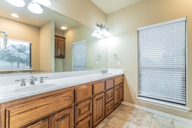 full bath with double vanity, a sink, baseboards, and tile patterned floors