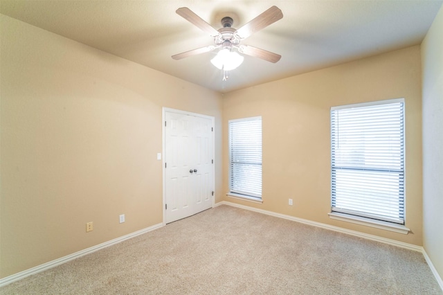 spare room featuring carpet flooring, ceiling fan, a healthy amount of sunlight, and baseboards