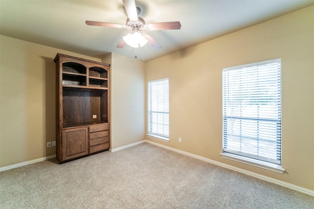 spare room featuring a ceiling fan, baseboards, and light carpet