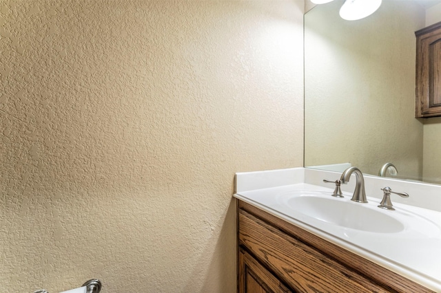 bathroom featuring a textured wall and vanity