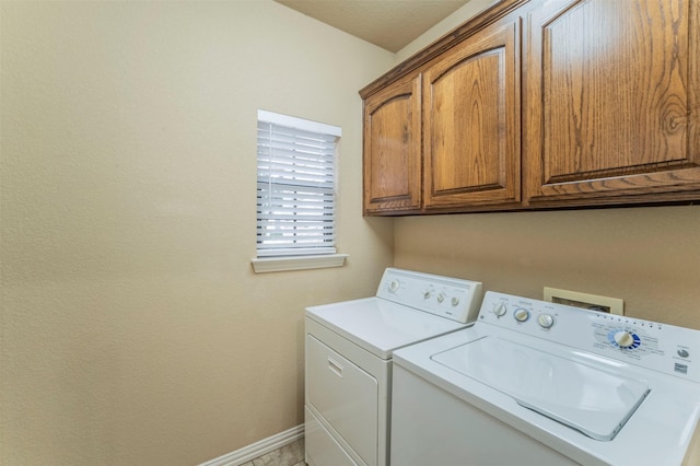 clothes washing area featuring cabinet space, baseboards, and washing machine and dryer