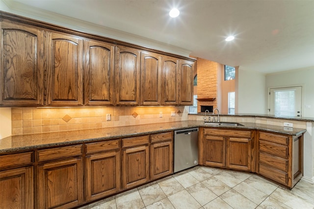 kitchen featuring a sink, dark stone counters, decorative backsplash, and stainless steel dishwasher