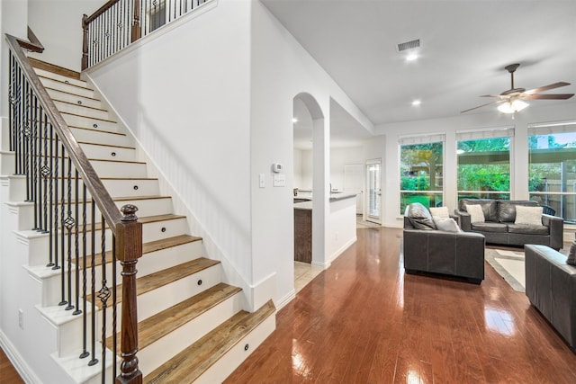 living room with ceiling fan, visible vents, arched walkways, stairs, and hardwood / wood-style floors