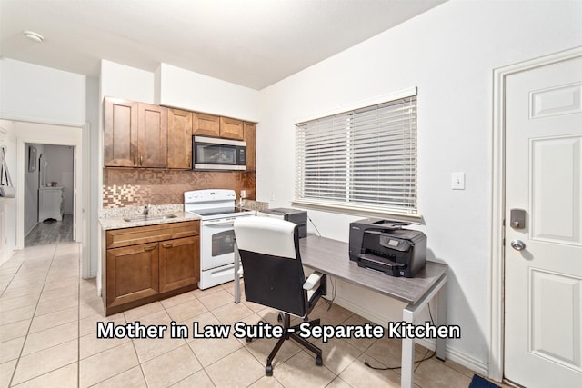 kitchen with decorative backsplash, electric range, stainless steel microwave, and brown cabinetry