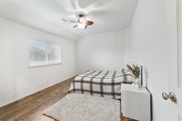 bedroom with a ceiling fan, baseboards, wood finished floors, lofted ceiling, and visible vents