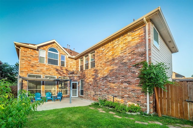 rear view of property featuring fence, a patio, a lawn, and brick siding