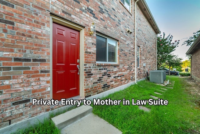 property entrance featuring central air condition unit and brick siding