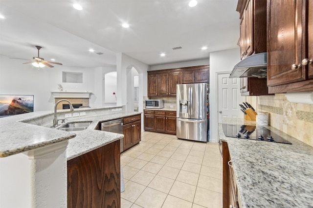 kitchen with appliances with stainless steel finishes, a sink, arched walkways, a ceiling fan, and under cabinet range hood