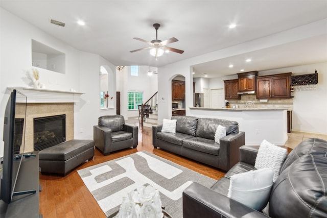 living area featuring visible vents, a ceiling fan, light wood-style floors, recessed lighting, and arched walkways