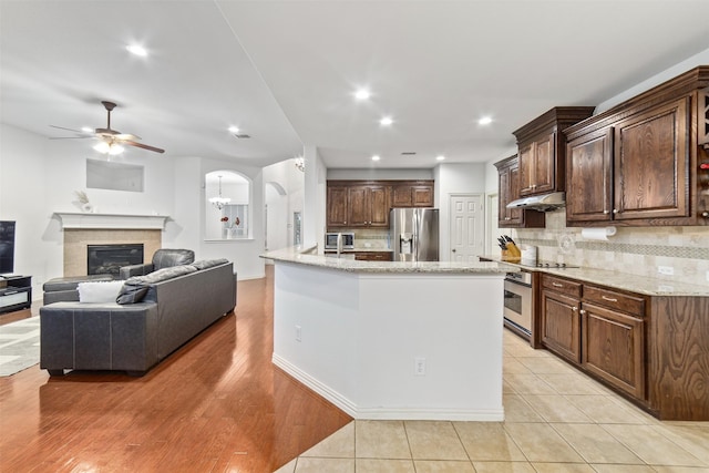 kitchen with backsplash, ceiling fan, appliances with stainless steel finishes, and light stone countertops
