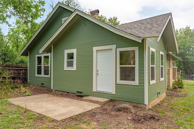 back of house with crawl space, a chimney, a patio area, fence, and a shingled roof