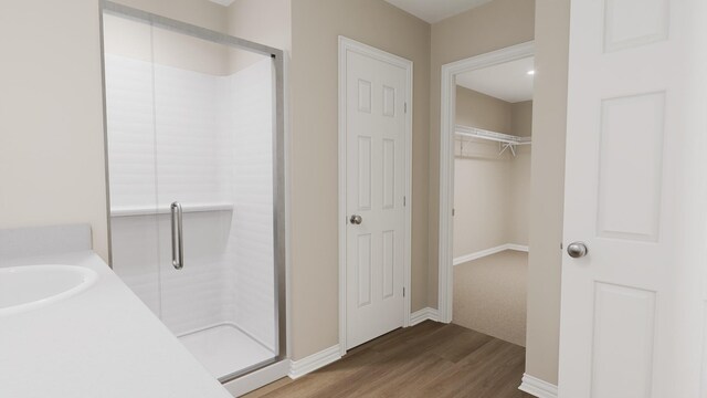full bathroom featuring a sink, a stall shower, and wood finished floors