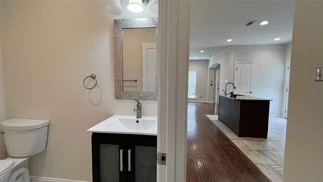 bathroom with visible vents, a sink, two vanities, and toilet