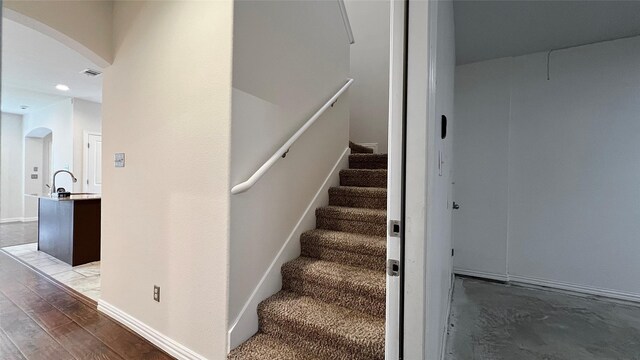 stairs featuring arched walkways, wood finished floors, and visible vents