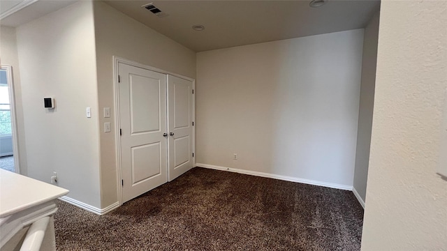 hall with baseboards, visible vents, and dark colored carpet