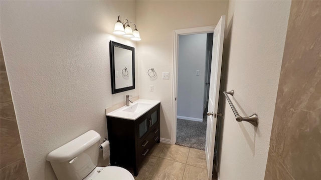 bathroom with vanity, tile patterned flooring, a textured wall, and toilet