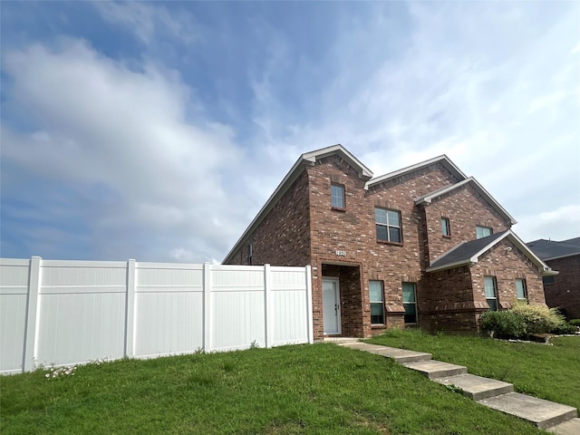 view of front of home featuring brick siding, a front lawn, and fence